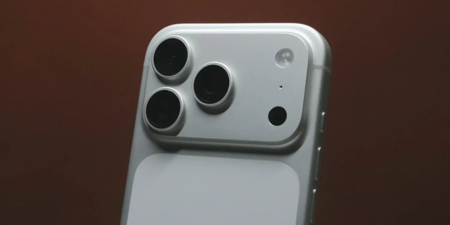 Close-up of a silver iPhone Pro rear camera module with three lenses, flash, and sensors.
